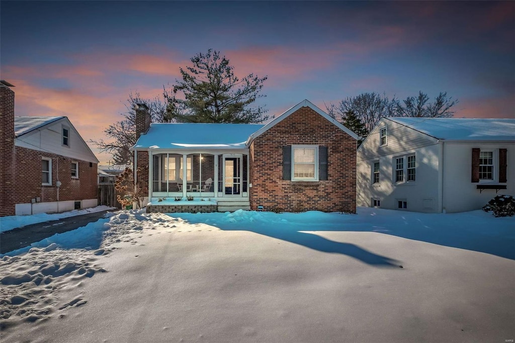 snow covered house with a sunroom