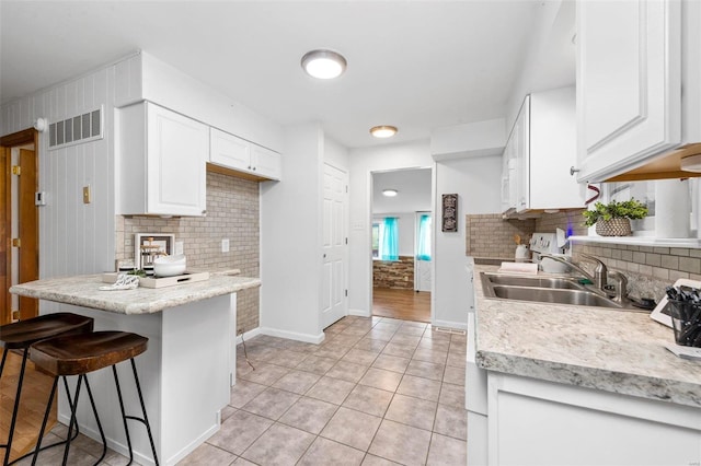 kitchen featuring sink, white cabinetry, a breakfast bar area, and light tile patterned flooring