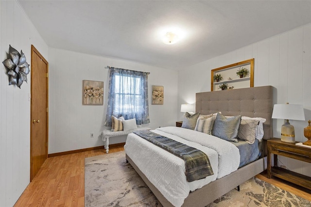 bedroom featuring wooden walls and light hardwood / wood-style floors