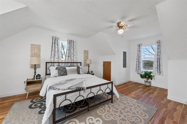 bedroom with lofted ceiling, hardwood / wood-style floors, multiple windows, and ceiling fan