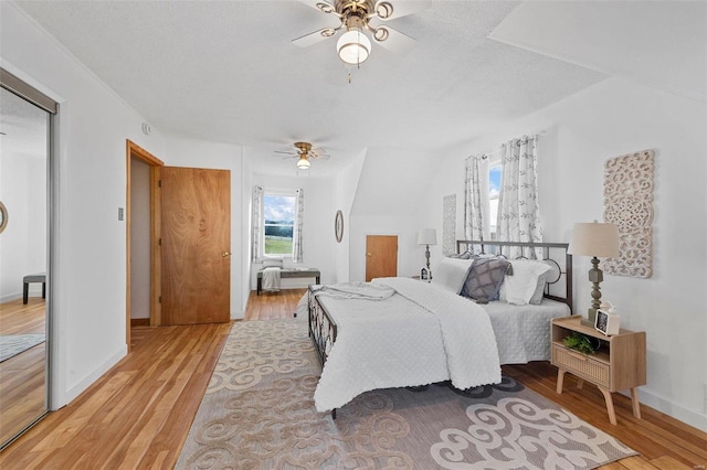 bedroom featuring light hardwood / wood-style floors, a textured ceiling, and ceiling fan