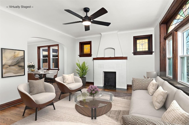 living room featuring ceiling fan, hardwood / wood-style floors, and a brick fireplace