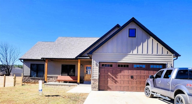 view of front of property featuring driveway, stone siding, a garage, and board and batten siding