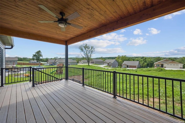 wooden deck with a residential view, a lawn, and a ceiling fan