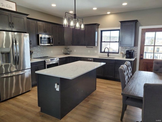 kitchen with appliances with stainless steel finishes, a healthy amount of sunlight, a sink, and light wood finished floors