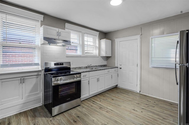 kitchen featuring sink, light hardwood / wood-style flooring, stainless steel appliances, white cabinets, and stone countertops