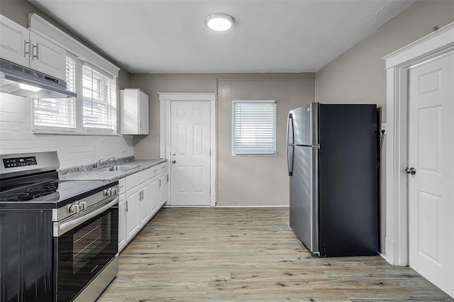 kitchen with sink, white cabinetry, light wood-type flooring, appliances with stainless steel finishes, and backsplash