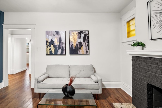 living room with a brick fireplace and dark hardwood / wood-style flooring