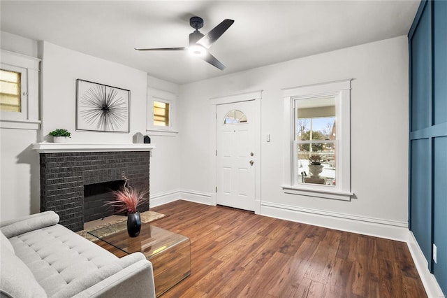 living room featuring ceiling fan, dark hardwood / wood-style floors, and a brick fireplace