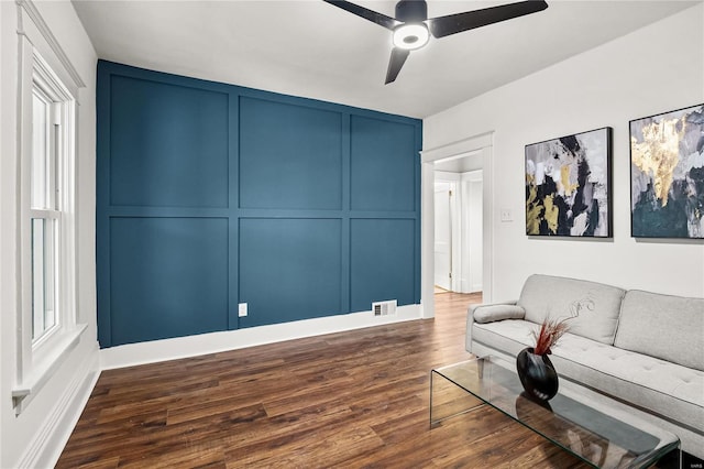 living room with ceiling fan and dark wood-type flooring