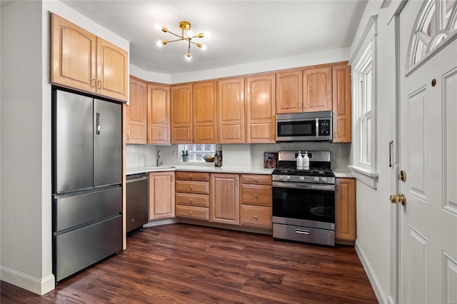 kitchen featuring dark hardwood / wood-style flooring, stainless steel appliances, decorative backsplash, light brown cabinetry, and a notable chandelier