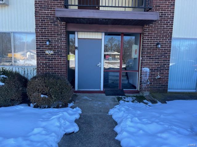 snow covered property entrance featuring a balcony