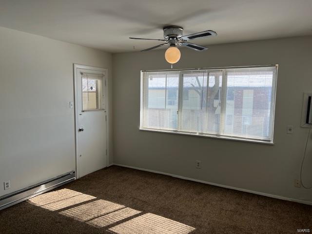 carpeted empty room featuring a healthy amount of sunlight, ceiling fan, and a baseboard radiator