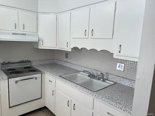 kitchen featuring backsplash, range hood, white cabinets, and sink