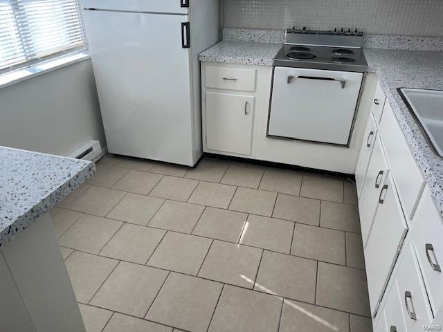 kitchen with white appliances, white cabinetry, and light tile patterned floors