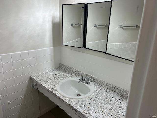 bathroom with sink and tile walls