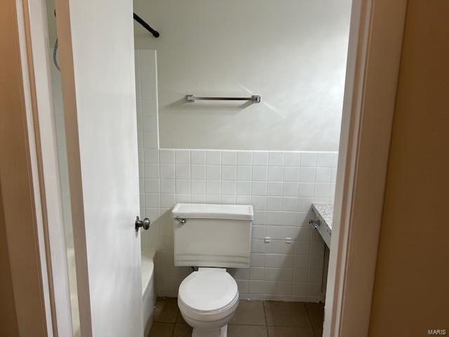 bathroom with tile walls, tile patterned floors, and toilet