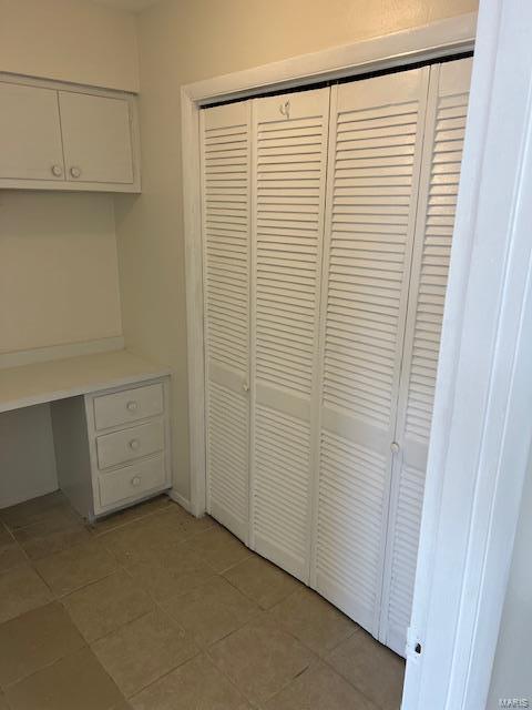 unfurnished office featuring built in desk and light tile patterned flooring