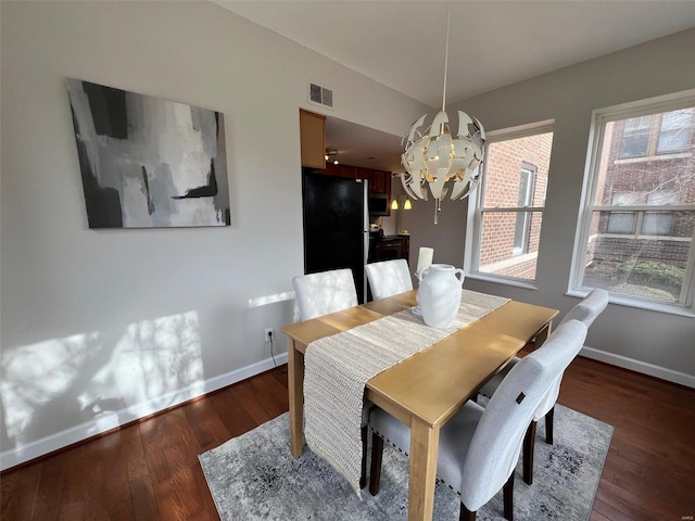 dining area featuring dark hardwood / wood-style flooring, plenty of natural light, and a notable chandelier