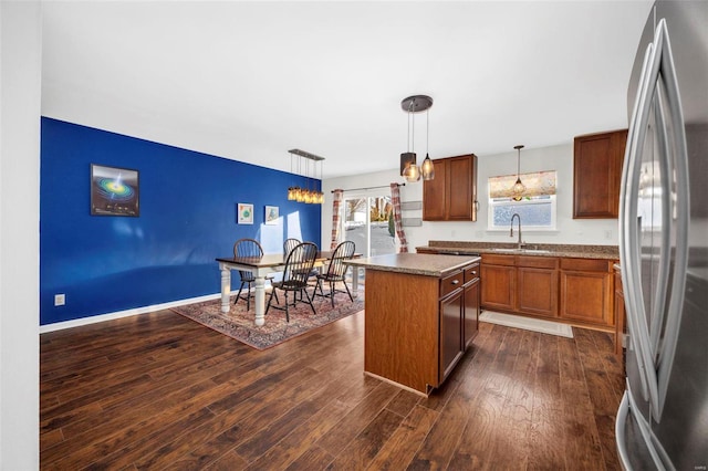 kitchen featuring sink, stainless steel fridge, decorative light fixtures, and a kitchen island