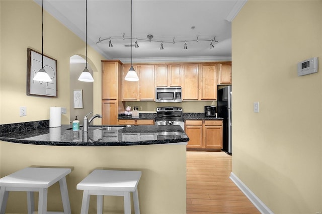 kitchen featuring pendant lighting, stainless steel appliances, dark stone countertops, kitchen peninsula, and crown molding