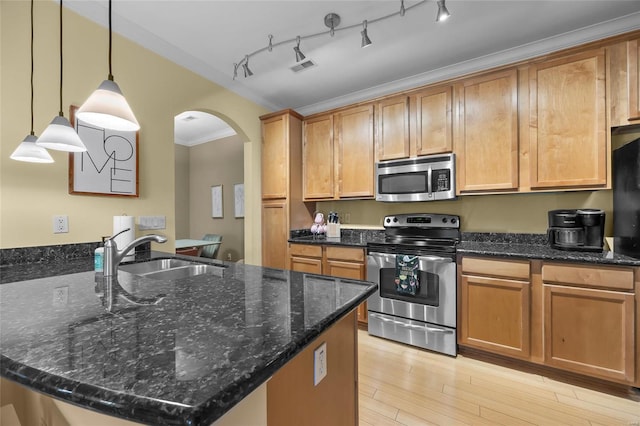 kitchen with hanging light fixtures, sink, dark stone counters, ornamental molding, and stainless steel appliances