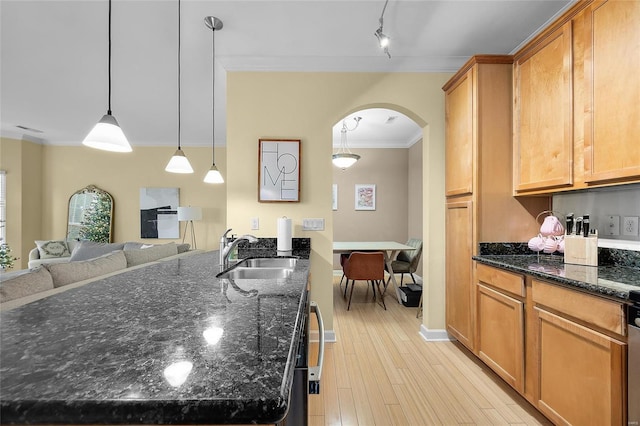 kitchen with sink, decorative light fixtures, dark stone counters, and ornamental molding