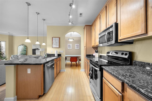 kitchen with pendant lighting, dark stone counters, ornamental molding, light hardwood / wood-style floors, and stainless steel appliances