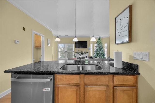 kitchen featuring crown molding, stainless steel dishwasher, hanging light fixtures, sink, and dark stone countertops