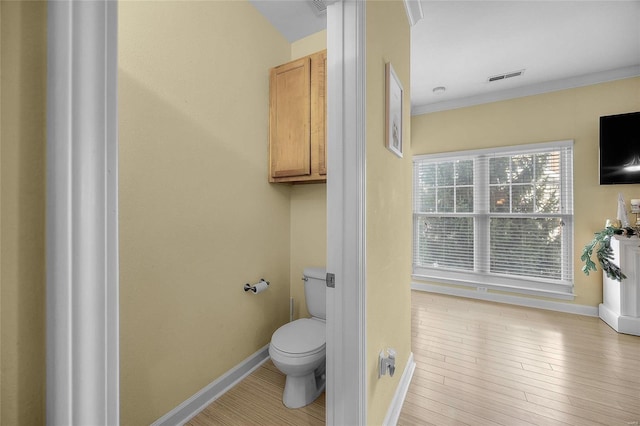 bathroom featuring hardwood / wood-style floors, toilet, and ornamental molding