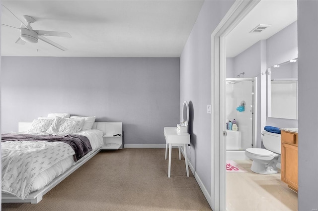 bedroom featuring light colored carpet, ensuite bath, and ceiling fan