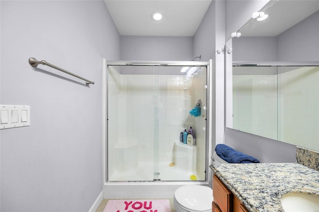 bathroom with a shower with shower door, toilet, and vanity