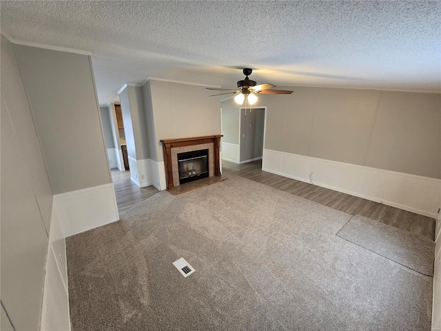 unfurnished living room featuring carpet, crown molding, ceiling fan, and a textured ceiling