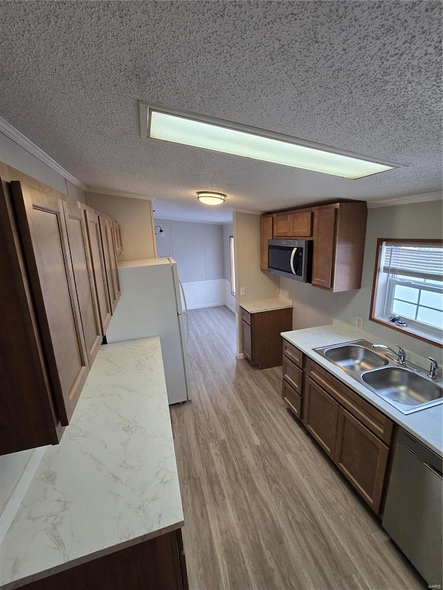 kitchen featuring a textured ceiling, ornamental molding, sink, and appliances with stainless steel finishes