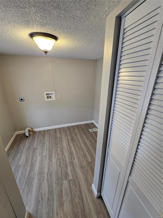 laundry area with electric dryer hookup, washer hookup, a textured ceiling, and light hardwood / wood-style floors