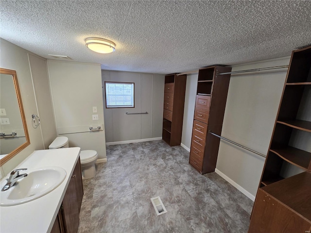 bathroom featuring vanity, a textured ceiling, and toilet