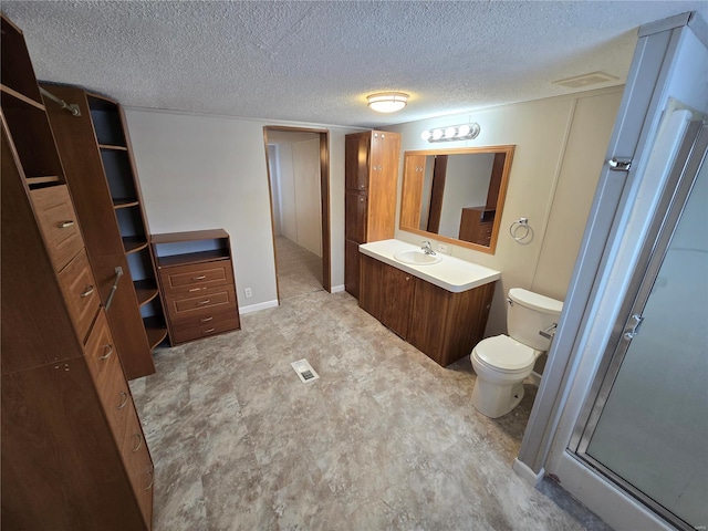 bathroom with a textured ceiling, vanity, an enclosed shower, and toilet