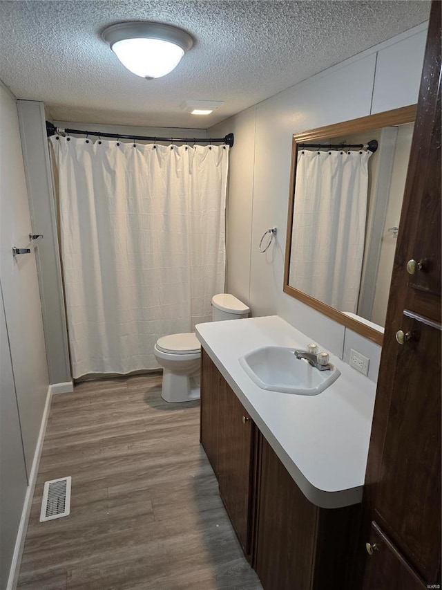 bathroom with toilet, vanity, a textured ceiling, and hardwood / wood-style flooring