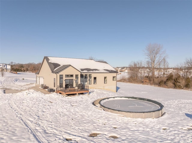 snow covered rear of property with a wooden deck