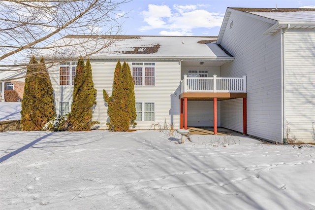 snow covered rear of property featuring a balcony