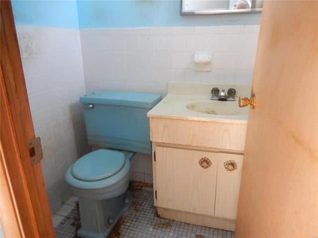 bathroom featuring tile patterned flooring, vanity, toilet, and tile walls