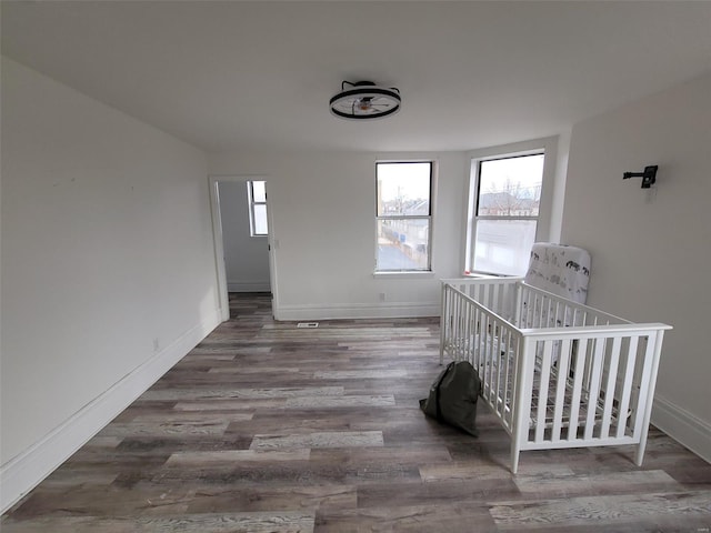 unfurnished bedroom featuring hardwood / wood-style floors and a nursery area