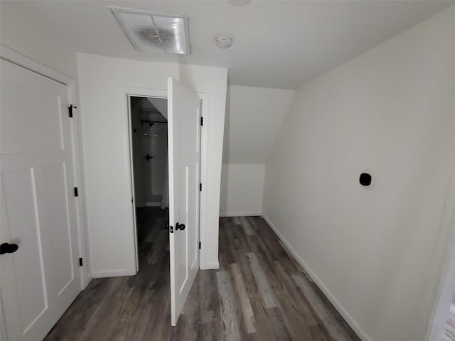 corridor with dark hardwood / wood-style flooring and vaulted ceiling