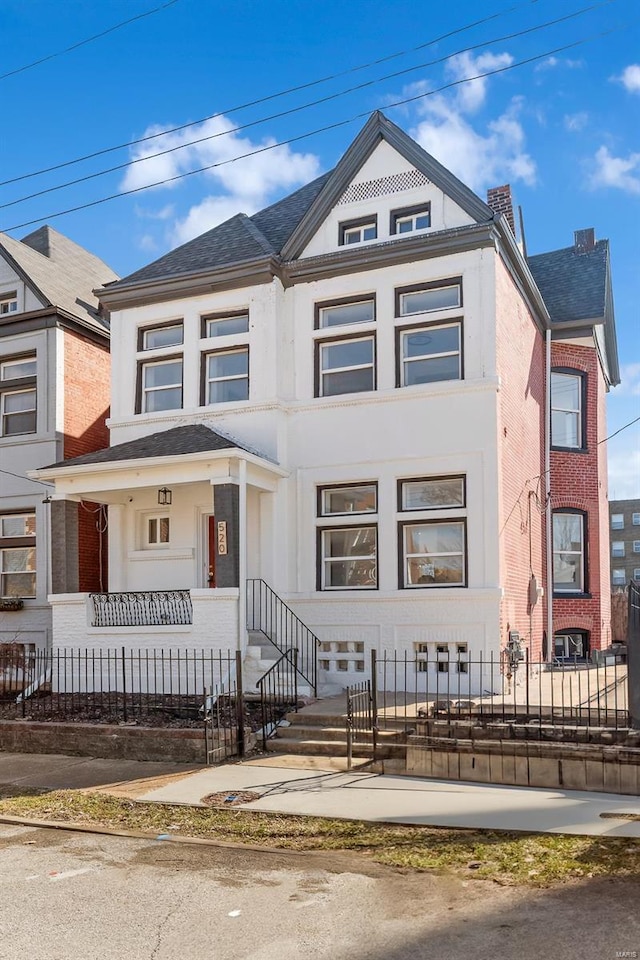 townhome / multi-family property featuring brick siding and a fenced front yard