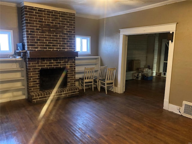 unfurnished living room with crown molding, a brick fireplace, plenty of natural light, and dark hardwood / wood-style flooring