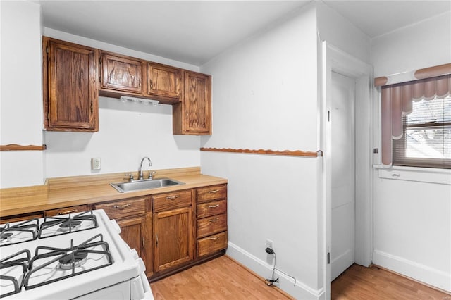 kitchen with sink, light hardwood / wood-style floors, and white gas range