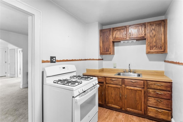 kitchen featuring sink, light colored carpet, and white gas stove