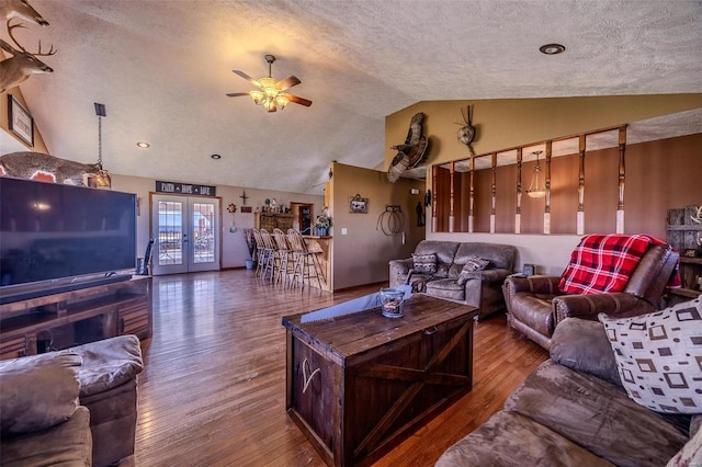 living room featuring ceiling fan, french doors, hardwood / wood-style floors, a textured ceiling, and vaulted ceiling