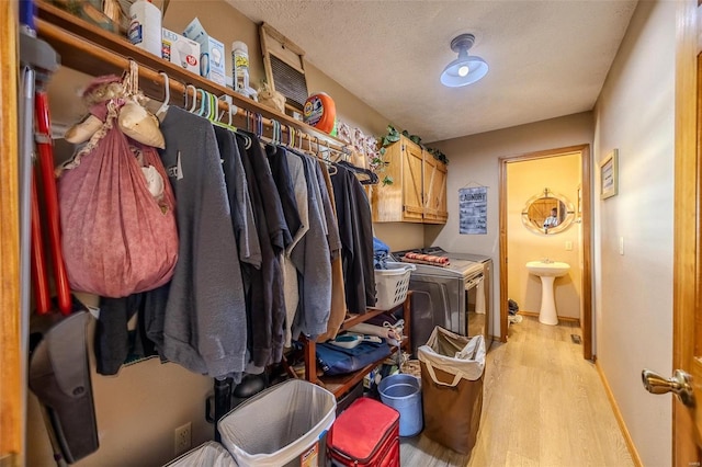 washroom with washer and clothes dryer, cabinets, sink, a textured ceiling, and light hardwood / wood-style floors