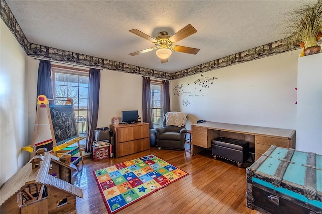 rec room featuring ceiling fan, a healthy amount of sunlight, wood-type flooring, and a textured ceiling